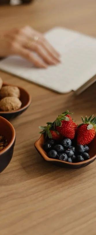 Mesa com caderno de anotações, castanhas e frutas vermelhas